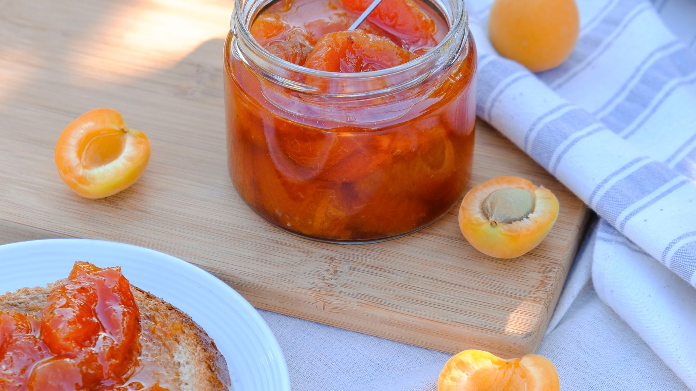 Pot de confiture d'abricot maison entouré d'abricots frais et d'une tartine