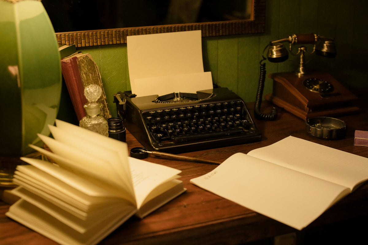Bureau vintage en bois sombre avec machine à écrire, téléphone rétro, livres et lampe verte sur fond de mur vert