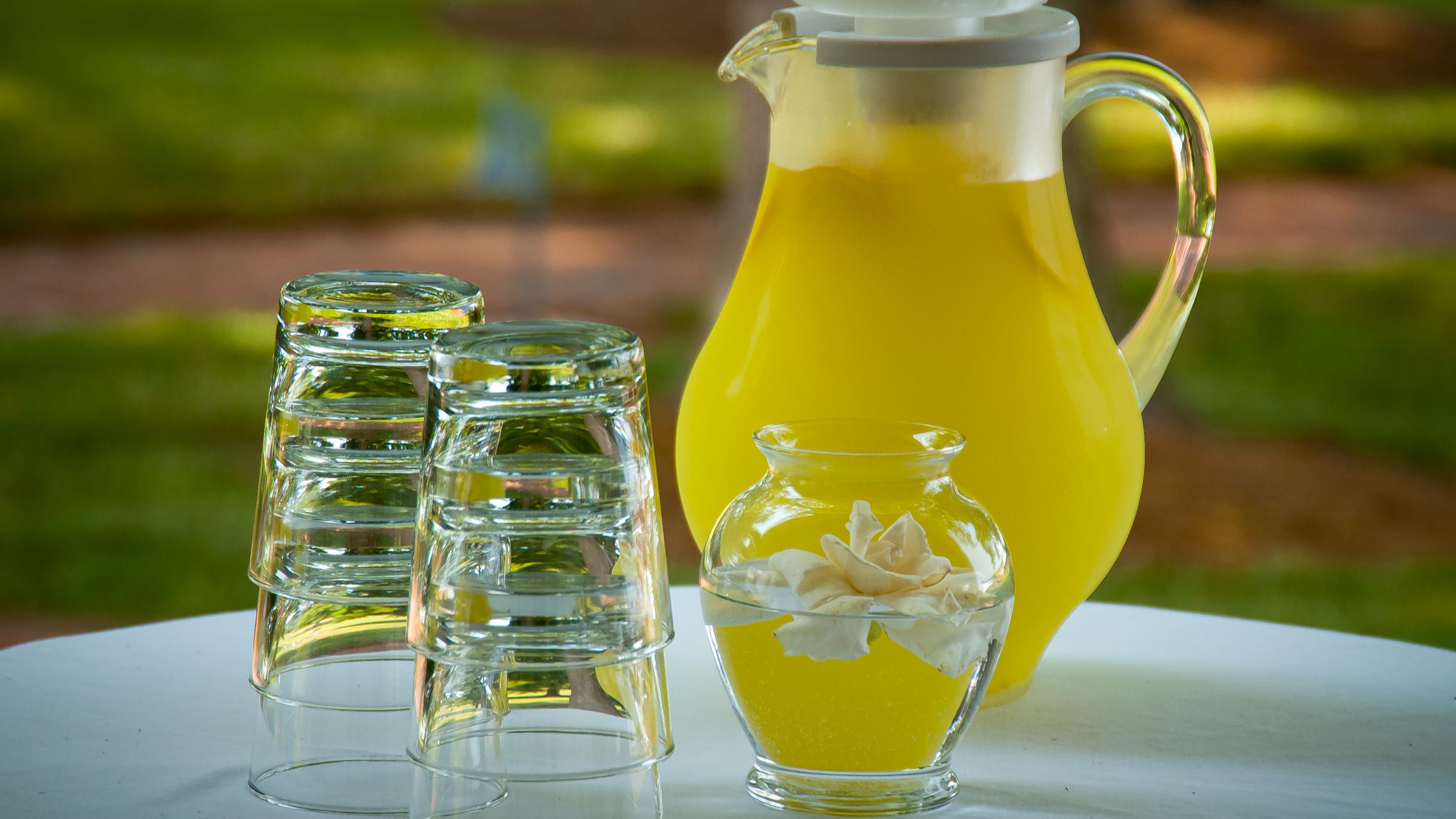 Carafe de limonade maison et verres retournés sur une table de jardin