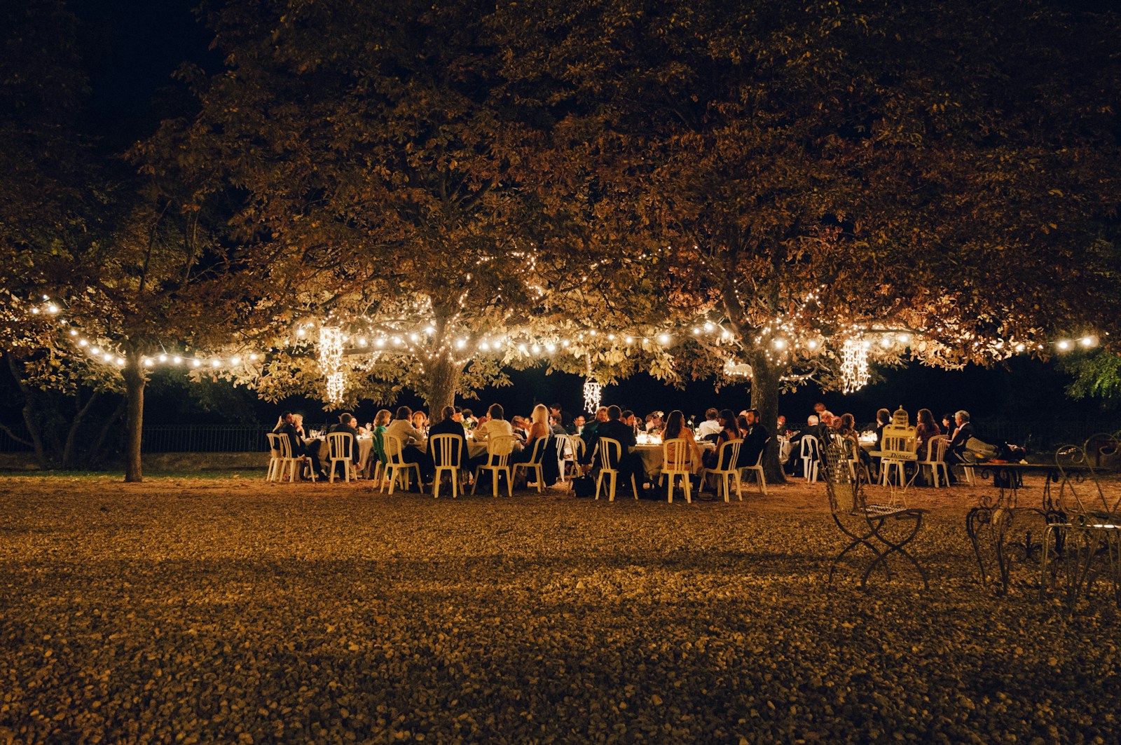 Grande table extérieure éclairée par des guirlandes pour une ambiance guinguette