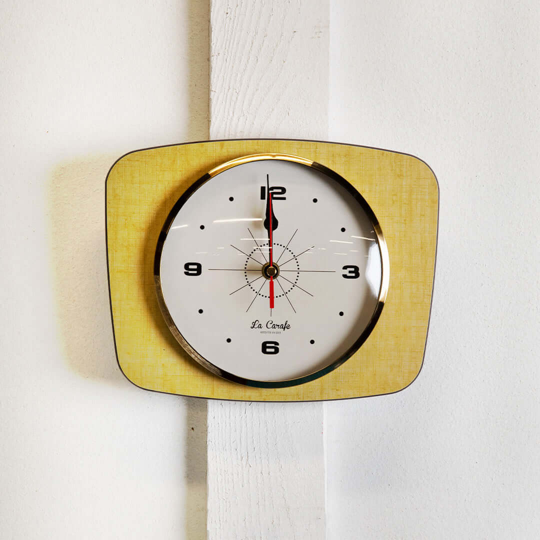 Horloge murale rectangulaire vintage au design rétro et couleurs passées, ajoutant une touche nostalgique à la décoration intérieure.
