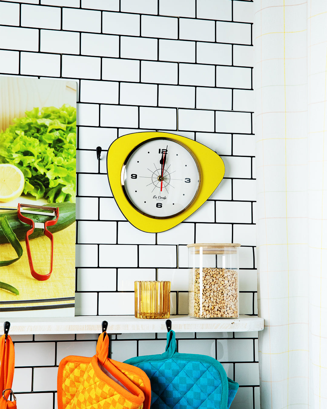Horloge de cuisine originale jaune sur un mur en carreaux blancs, accessoire parfait pour maîtriser les temps de cuisson en cuisine.