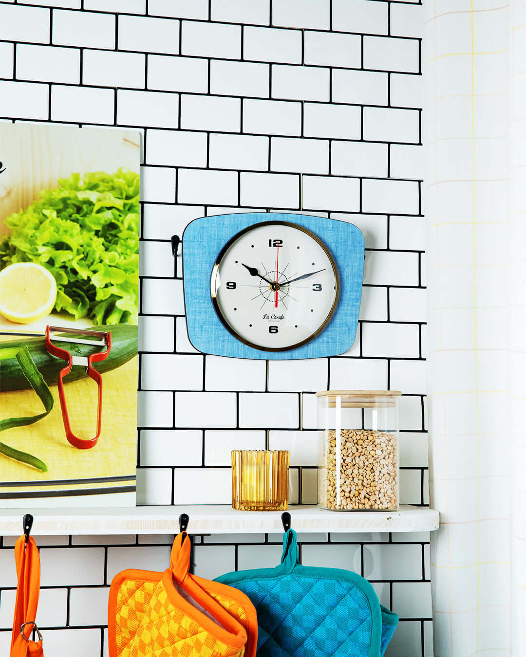 Horloge rectangulaire vintage bleue accrochée au mur de cuisine carrelée, ajoutant une touche rétro à la décoration.