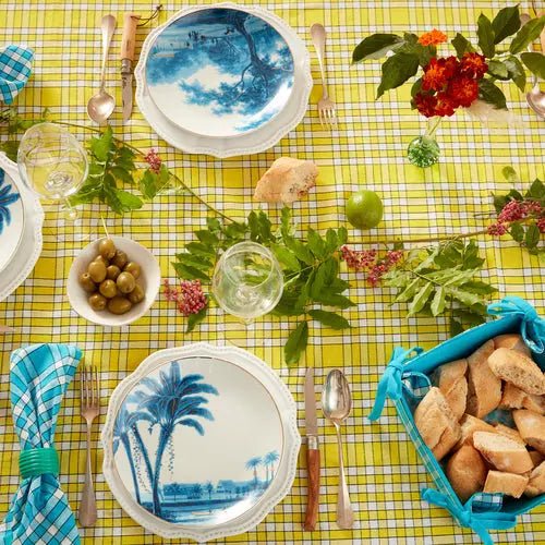 Table dressée avec nappe bistrot à carreaux, vaisselle bleue, olives et pain, ambiance conviviale.