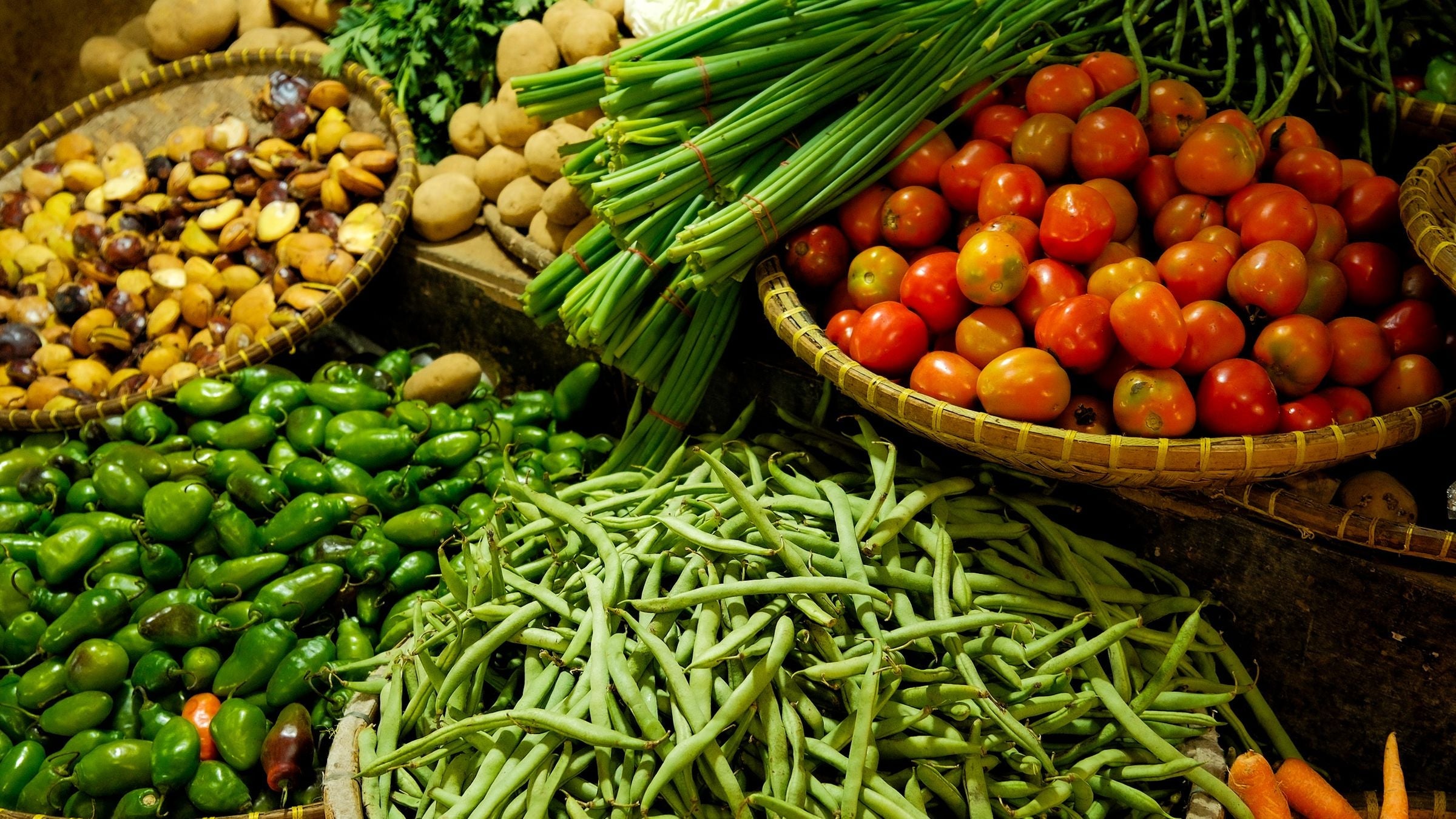 Étal de marché d'été avec tomates, haricots verts et légumes présentés dans des paniers en osier