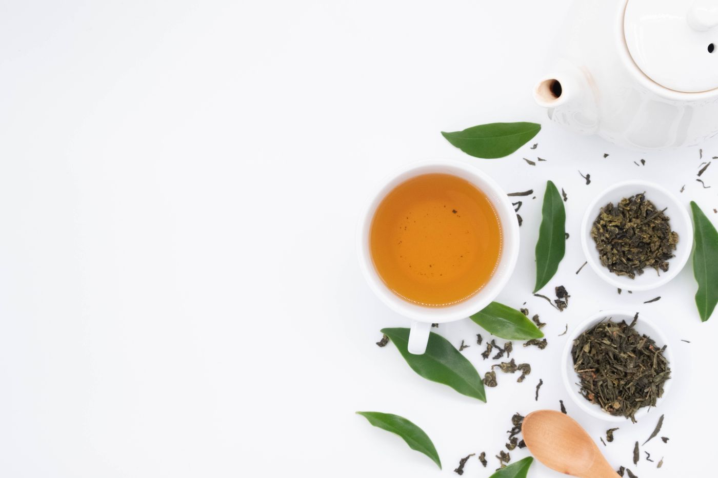 Feuilles de thé vert en vrac, bols et cuillère pour préparer une infusion