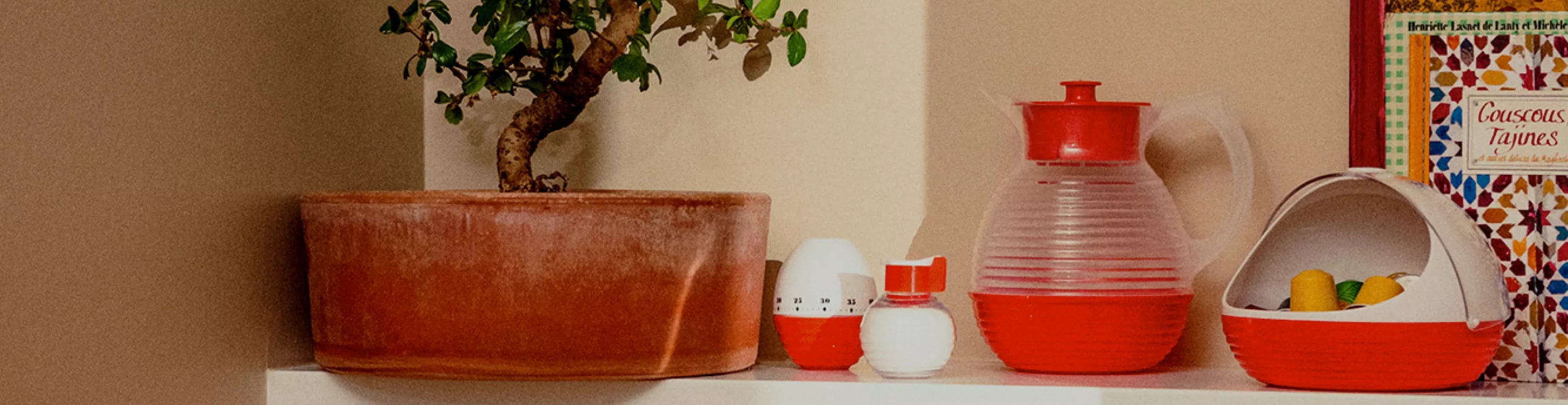 Accessoires cuisine et maison vintage La Carafe : carafes colorées, ustensiles inox et plateaux rétro sur étagère verte.