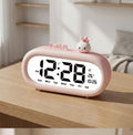 Réveil digital enfant rose avec figurine lapin, vue sur table en bois
