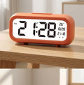 Réveil digital slim terracotta orange posé sur une table en bois