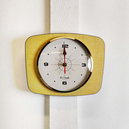 Horloge murale rectangulaire vintage au design rétro et couleurs passées, ajoutant une touche nostalgique à la décoration intérieure.