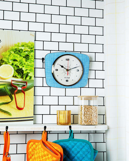 Horloge rectangulaire vintage bleue accrochée au mur de cuisine carrelée, ajoutant une touche rétro à la décoration.